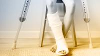 Child with cast on lower leg sitting with crutches